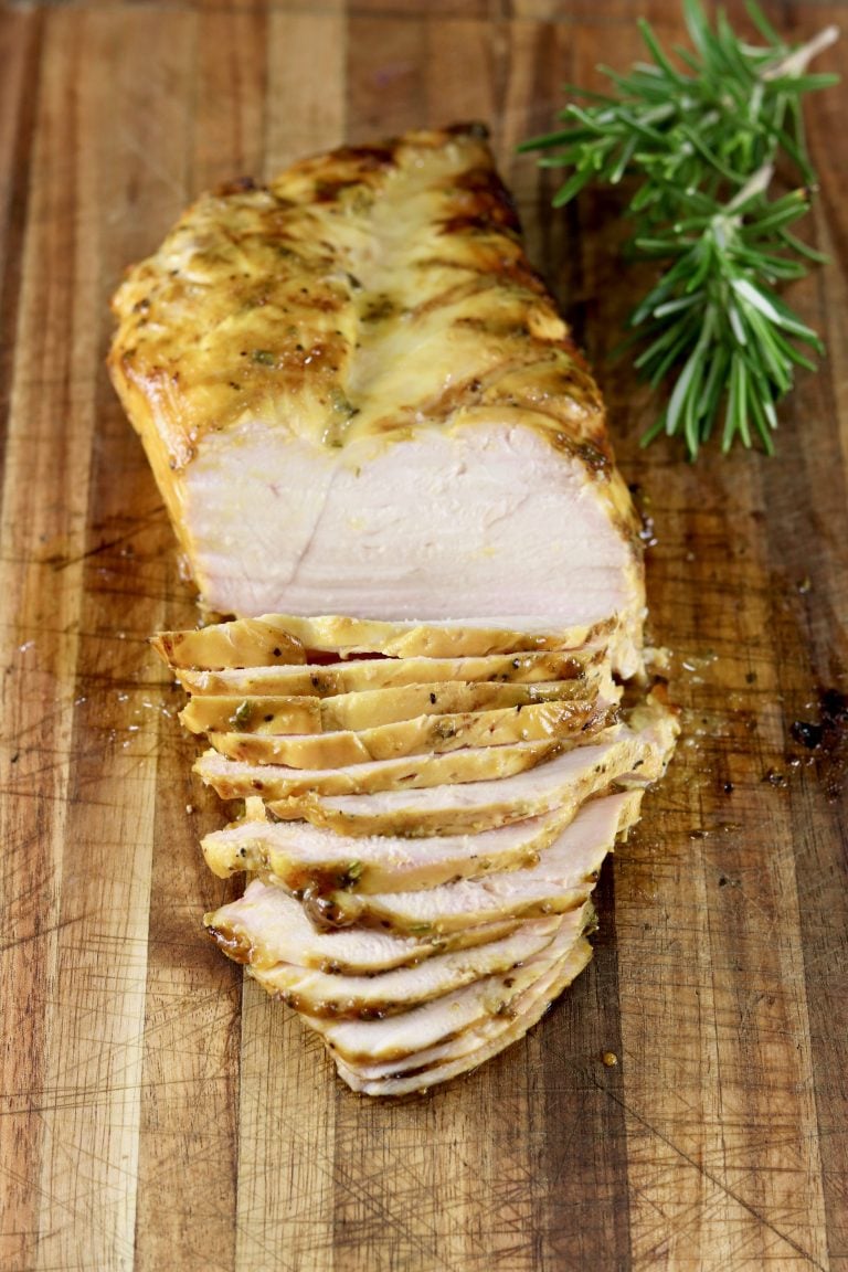 Mustard BBQ Chicken breast, sliced on cutting board with fresh rosemary