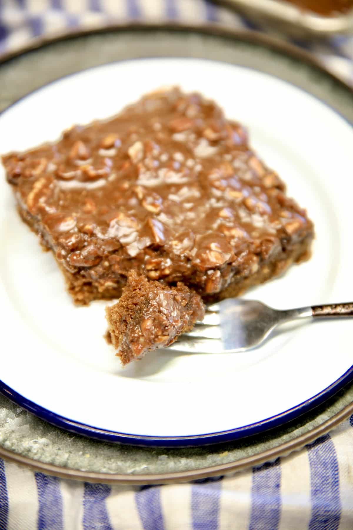 Slice of chocolate cake on a plate, bite on fork.