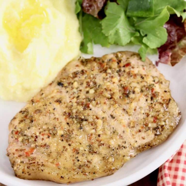 Pork chop on a plate with salad and mashed potatoes.