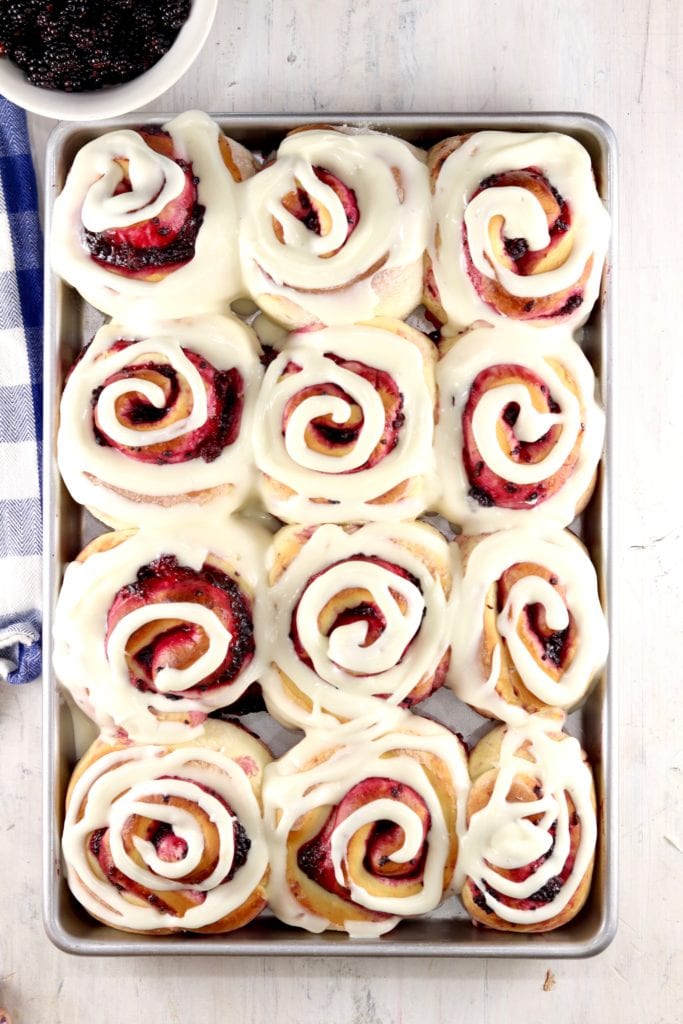 Cream cheese icing swirled over blackberry sweet rolls