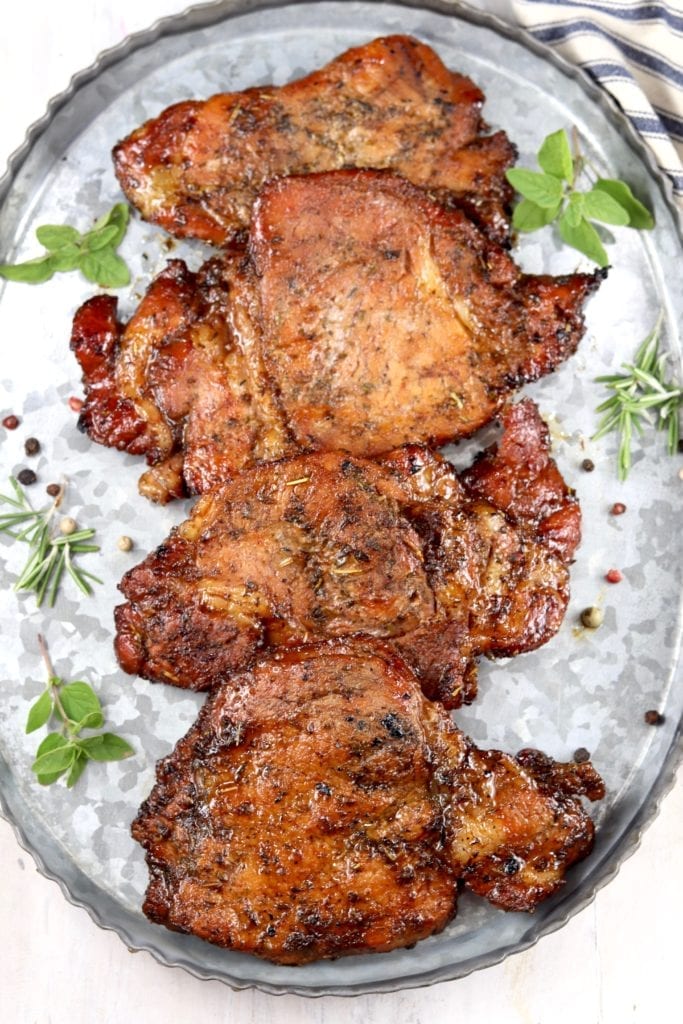Grilled Pork Chops with fresh herbs and peppercorns on a galvanized tray