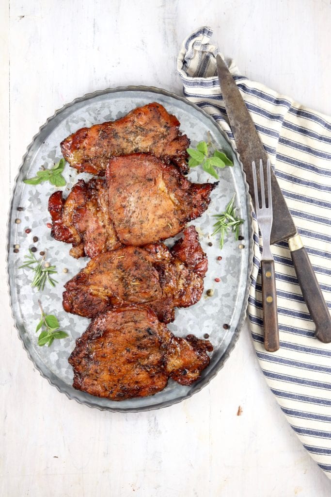 Platter of grilled pork chops with fork, knife and striped napkin