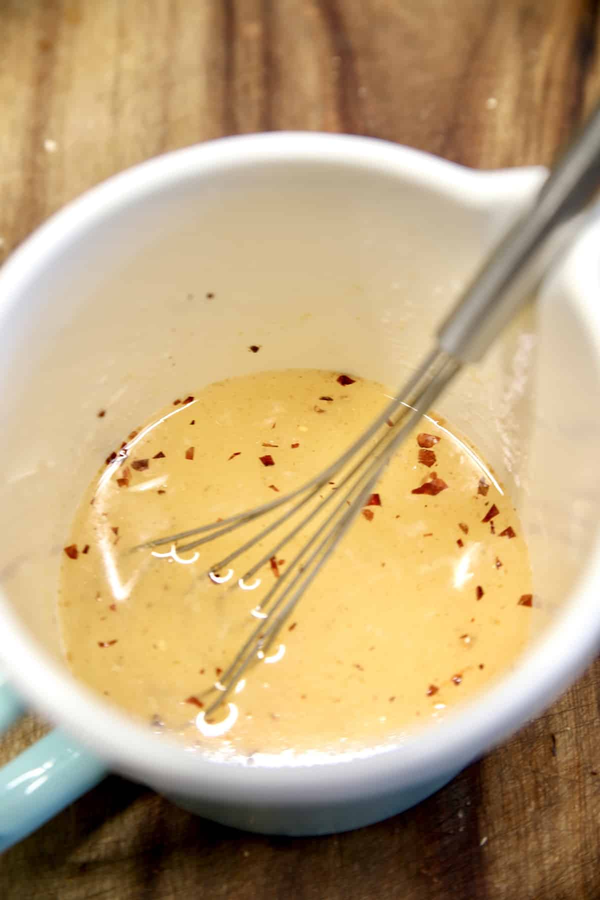 Thai Cucumber Salad dressing in a measuring cup with whisk.