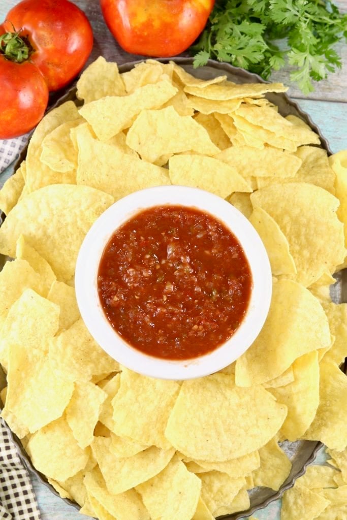 Platter of tortilla chips and white bowl of salsa