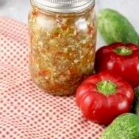 Pint jars of sweet pickle relish with red peppers and fresh cucumbers