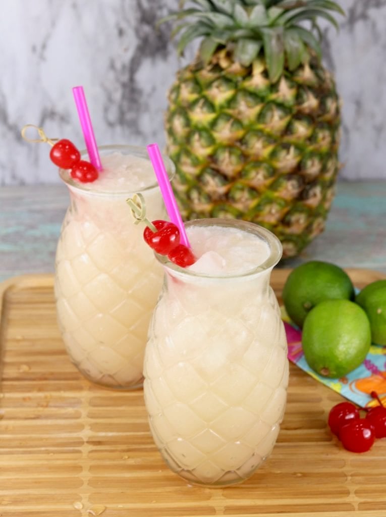 Wine cocktail served in pineapple glasses garnished with cherries and pink straws