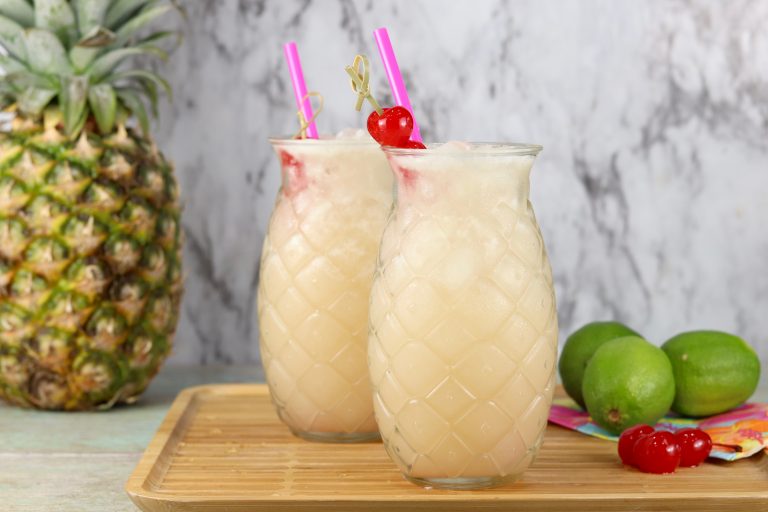 Cocktail wine punch served in pineapple glasses fresh limes, and pineapple in the back ground