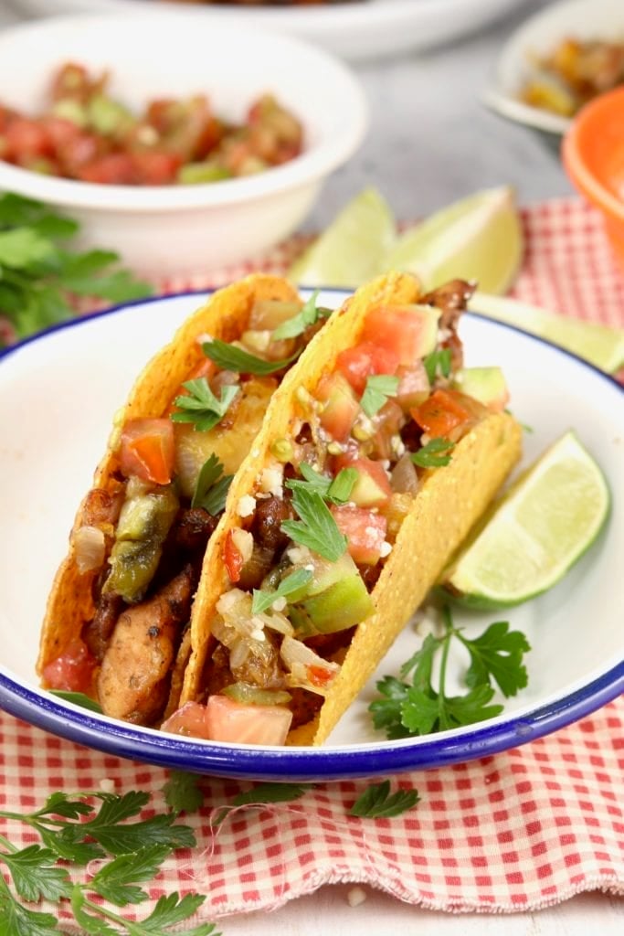 Plate of 2 tacos garnished with cilantro and a lime slice