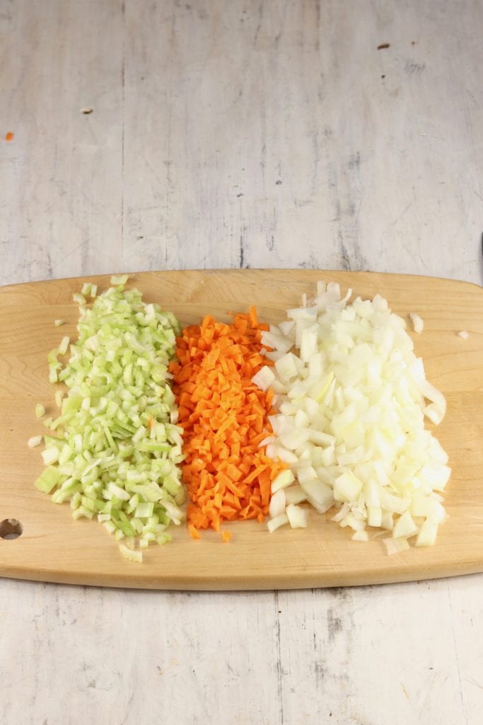 Cutting board with diced celery, diced carrots and diced onions