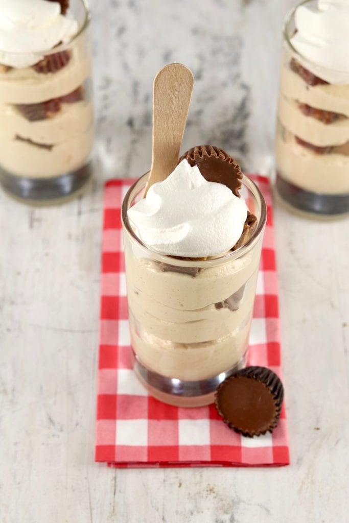 Overhead view of peanut butter parfait with peanut butter cups on a red check napkin