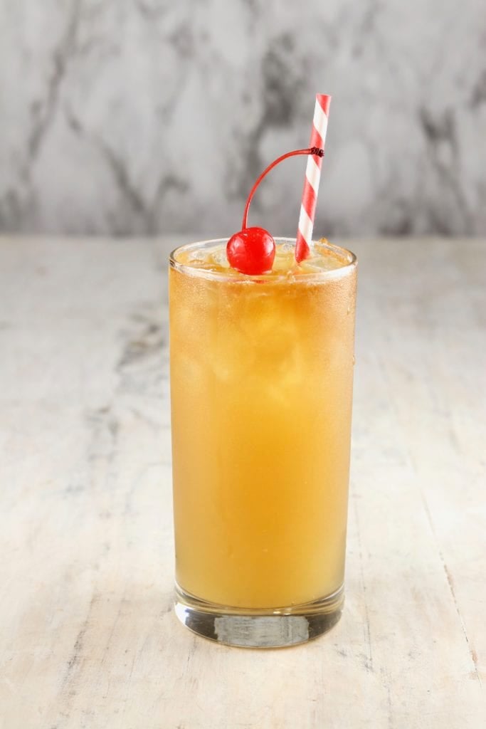 Glass of rum punch with a cherry and red stripe sraw
