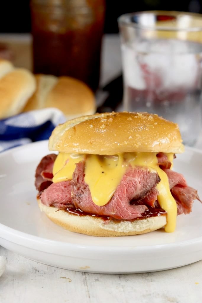 Rare roast beef sandwich on a bun with cheddar cheese sauce