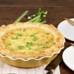 Bacon Quiche in a yellow pie plate garnished with green onions