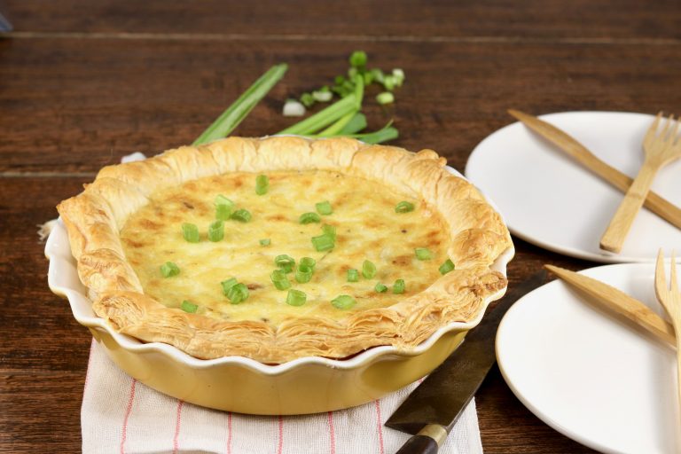 Bacon Quiche in a yellow pie plate garnished with green onions