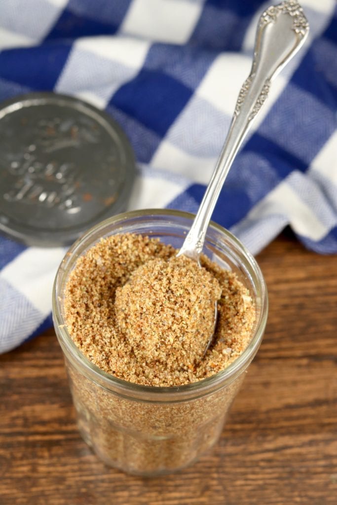 Jar of dry beef rub seasoning blend with a spoon