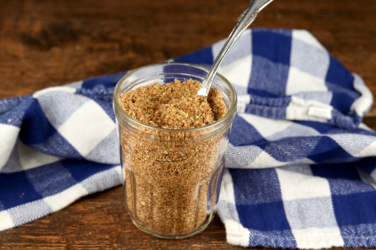 Jar of brown sugar and spices beef rub with a blue and white checked napkin