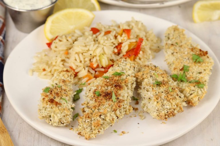 Baked fish sticks on a white plate with rice and fresh lemon slice
