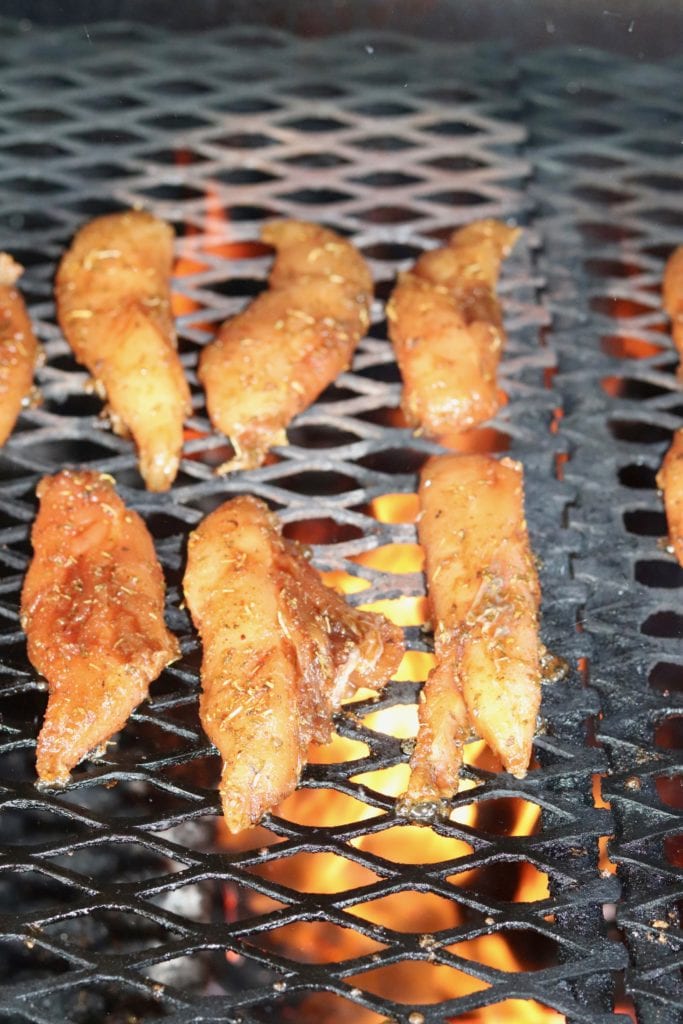 Marinated chicken tenders on a grill with fire below