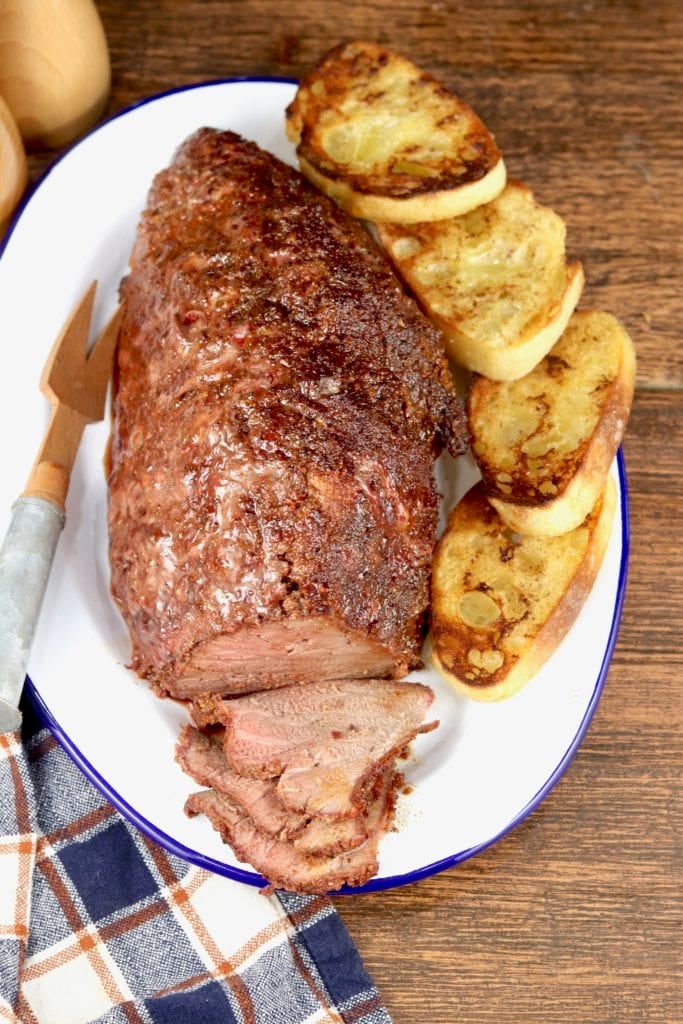 Sliced Roast Beef on a platter with slices of toasted baguette