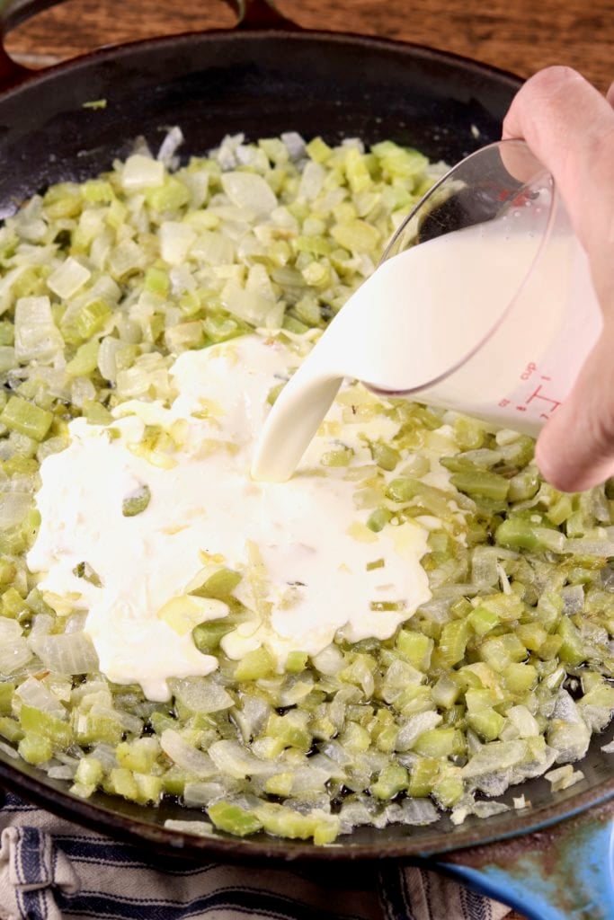 Adding cream to onion and celery mixture in a skillet