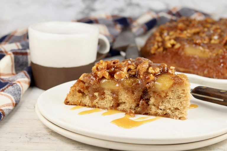 Slice of apple spice cake on a white plate with caramel drizzle