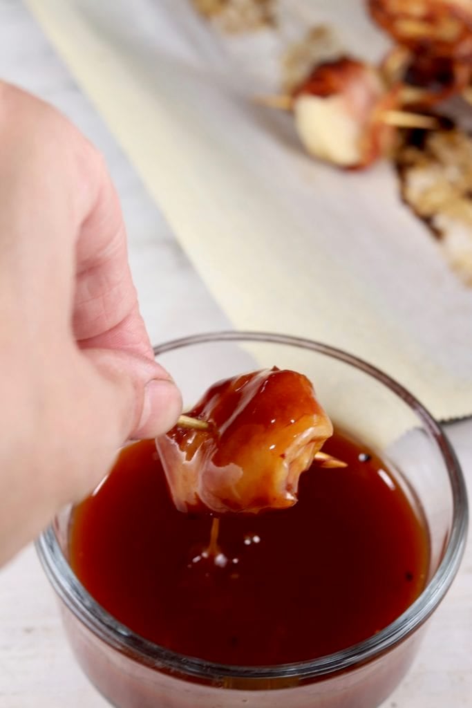 Dipping bacon wrapped water chestnuts into Barbecue Sauce Bowl