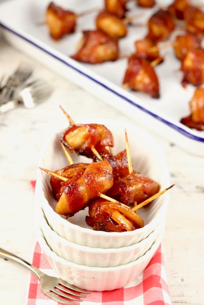 Bacon Wrapped Water Chestnuts are an incredibly delicious appetizer that is super simple to make for holidays, parties and game day get togethers. Only 3 ingredients in this easy appetizer! Oval dish of bacon wrapped water chestnuts