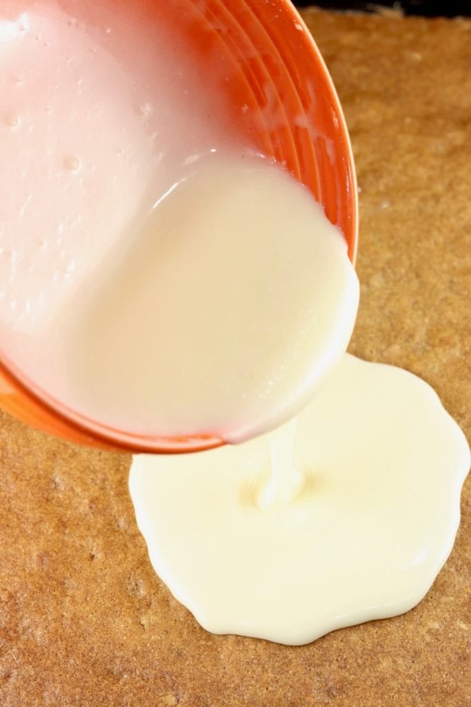 Pouring icing over sheet cake