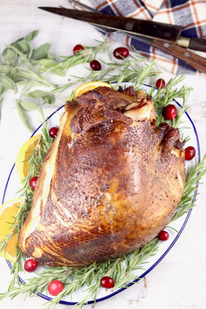 Smoked Turkey Breast on a platter with fresh rosemary and cranberries