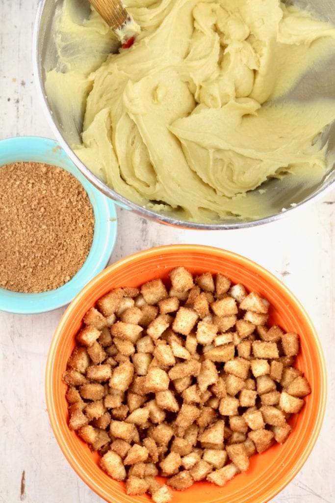 Bowl of cake batter, cinnamon apples and bowl of cinnamon sugar for apple fritter cake