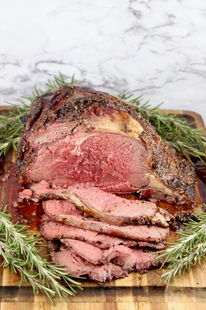 Prime Rib slices in front of roast on a cutting board