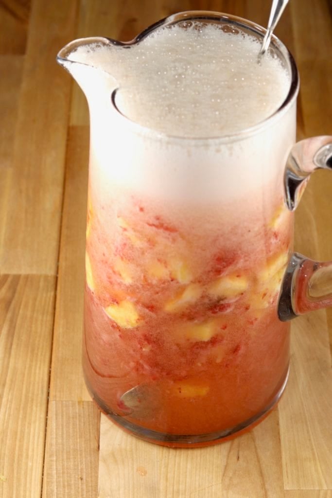 Ginger ale poured over pitcher of champagne and fruit