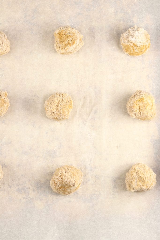 Molasses cookie dough balls on a parchment lined baking sheet