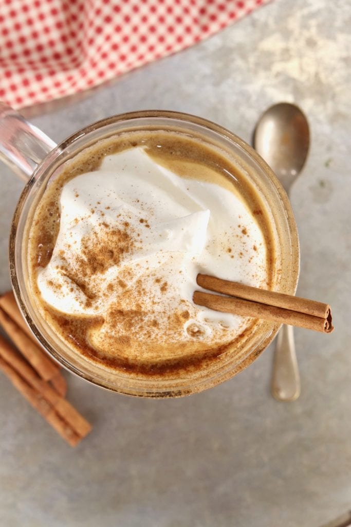 Overhead view of whipped cream topped buttered rum with a cinnamon stick