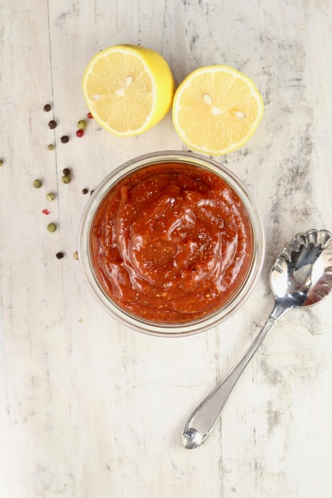 Bowl of cocktail sauce with spoon and sliced lemon
