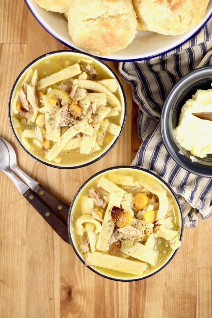 Homemade Chicken Noodle Soup in 2 bowls with a bowl of biscuits