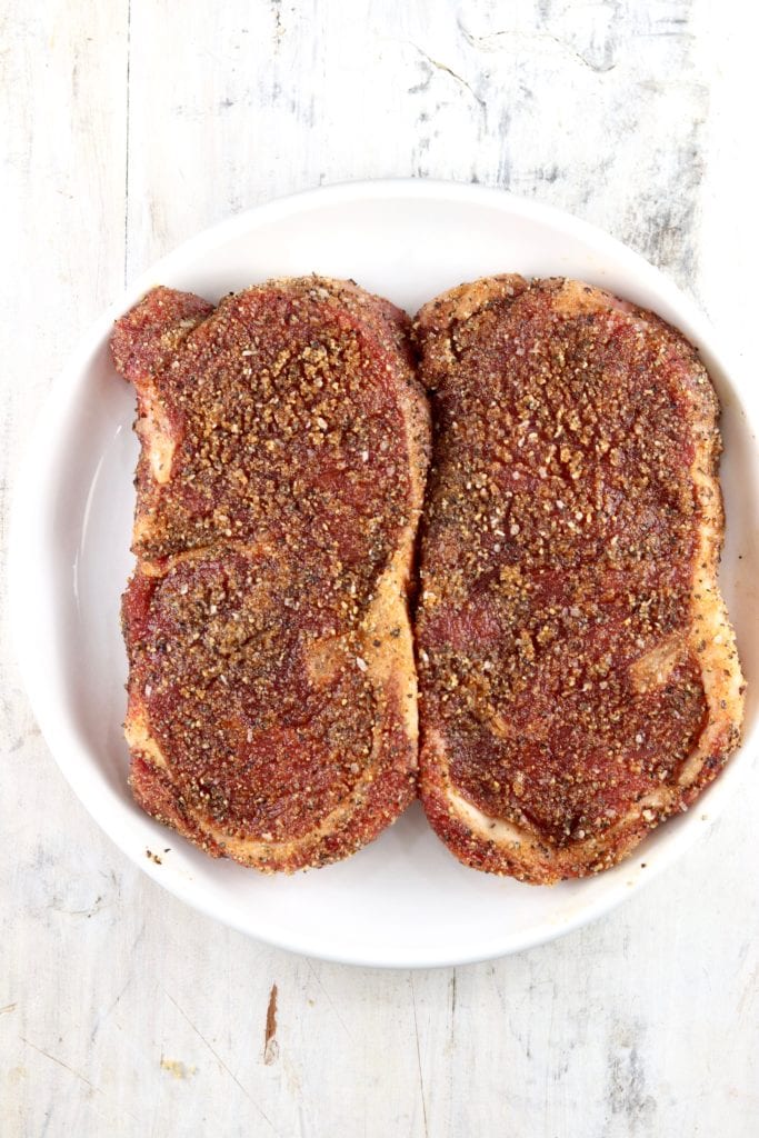 Seasoned ribeye steaks on a plate