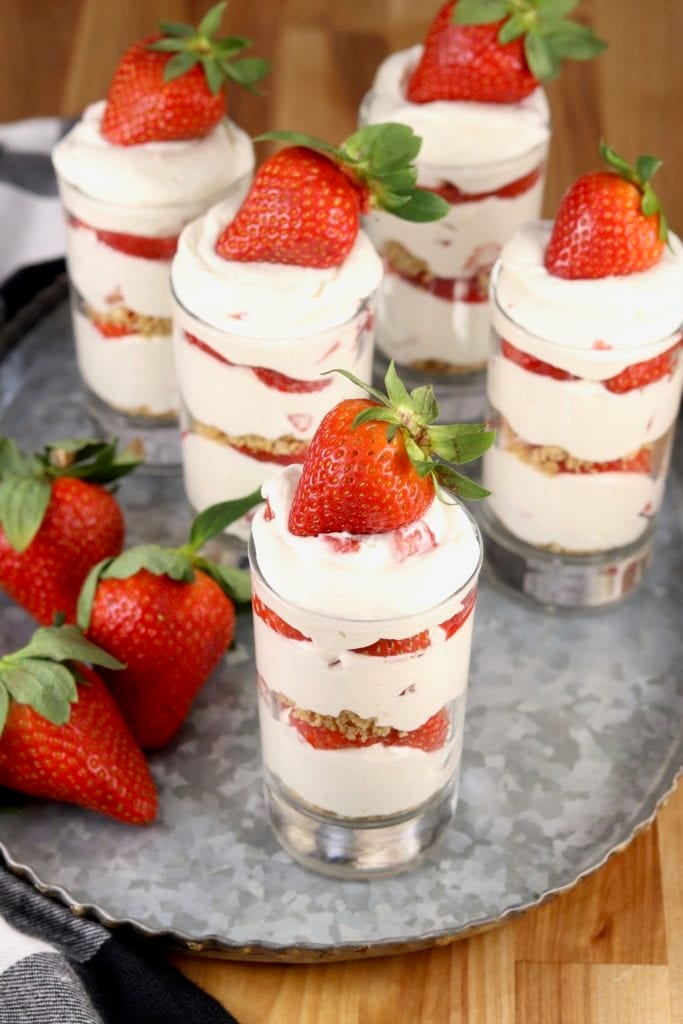 Tray of layered cheesecake parfaits with strawberry garnish