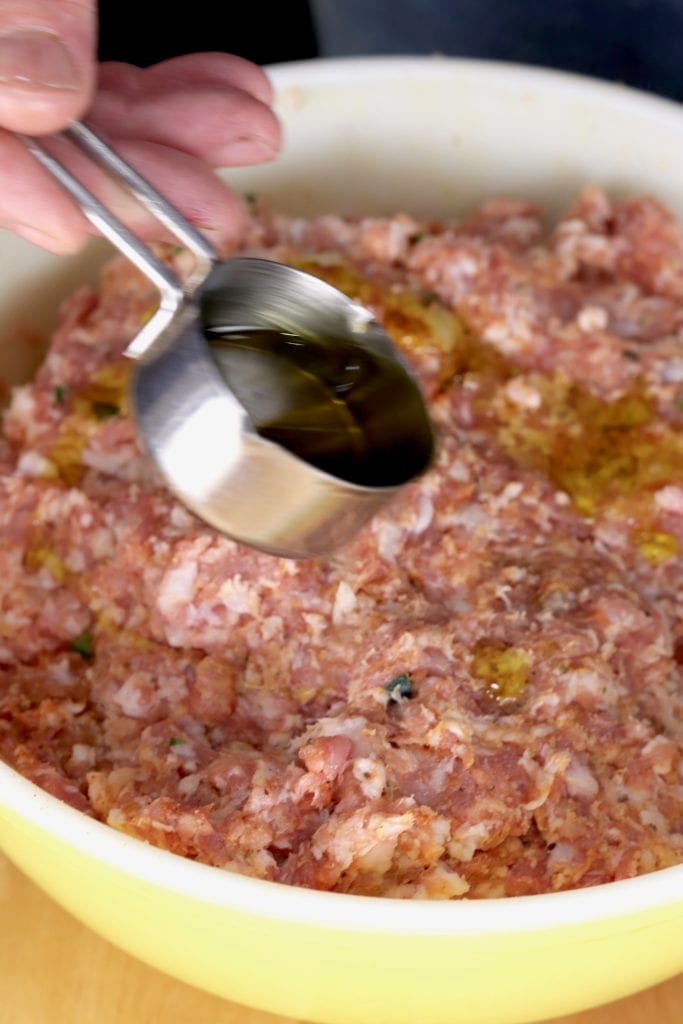 Adding olive oil to ground pork and spices mixture