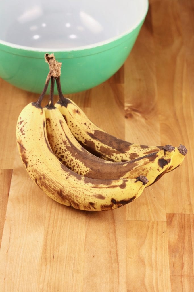 Ripe bananas on counter with a green bowl