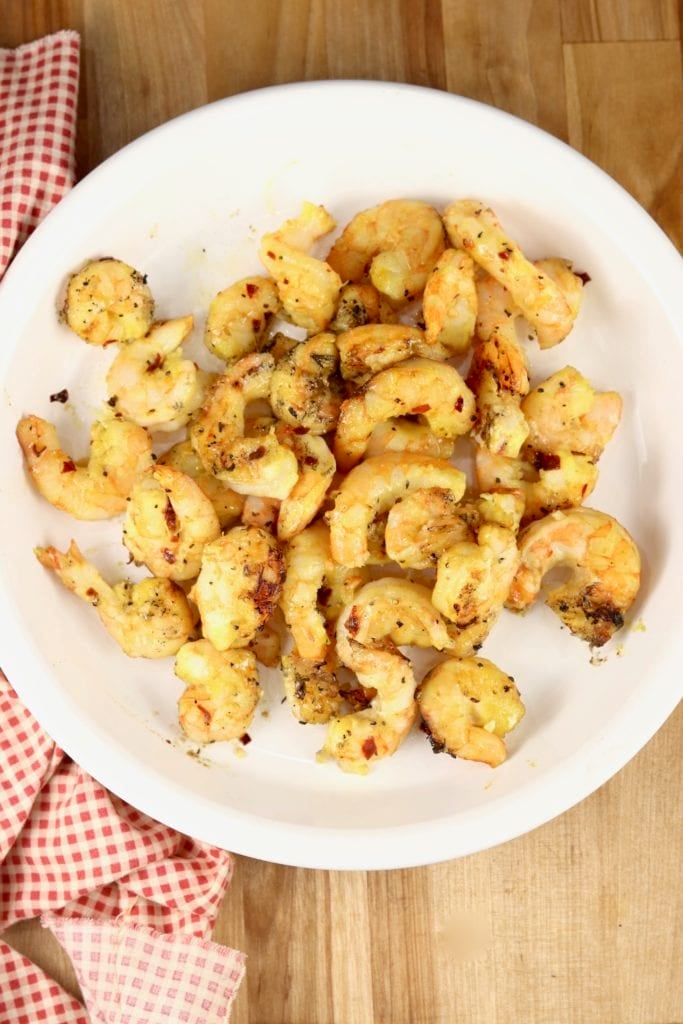 White plate of grilled honey mustard shrimp with a red checked napkin