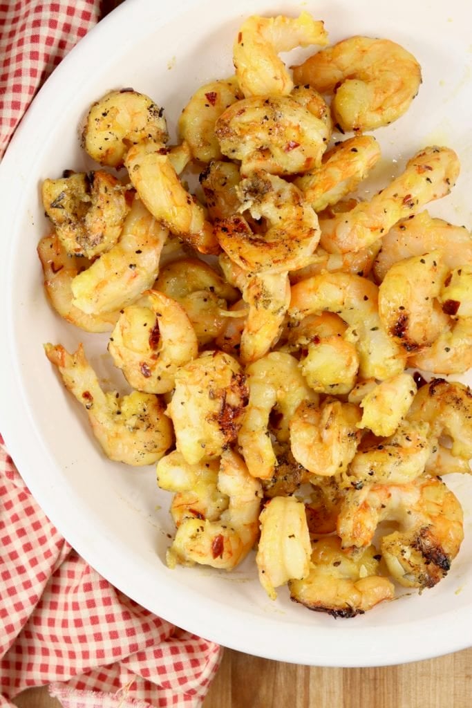 White pie plate filled with grilled shrimp coated in honey mustard sauce.