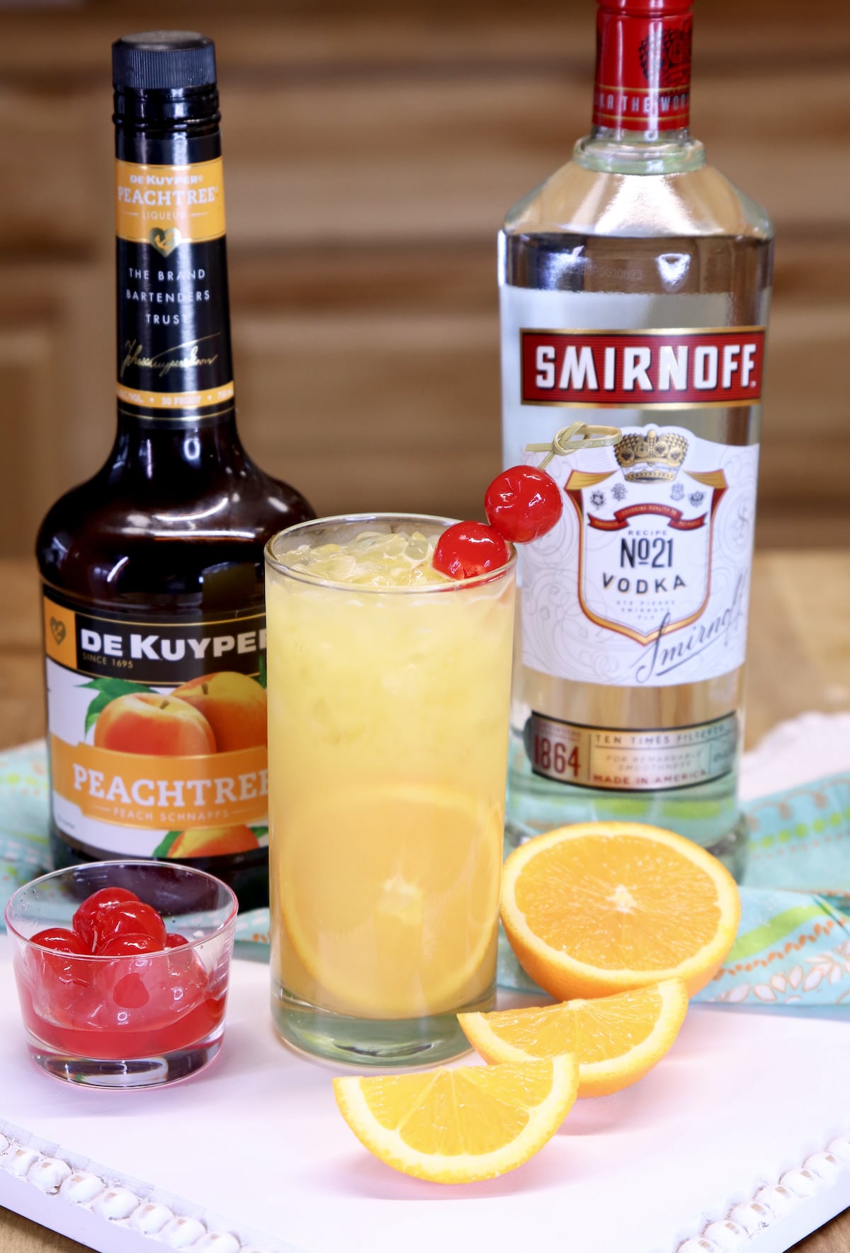 Fuzzy screwdriver cocktail in a glass with bottle of peach schnapps and bottle of vodka.