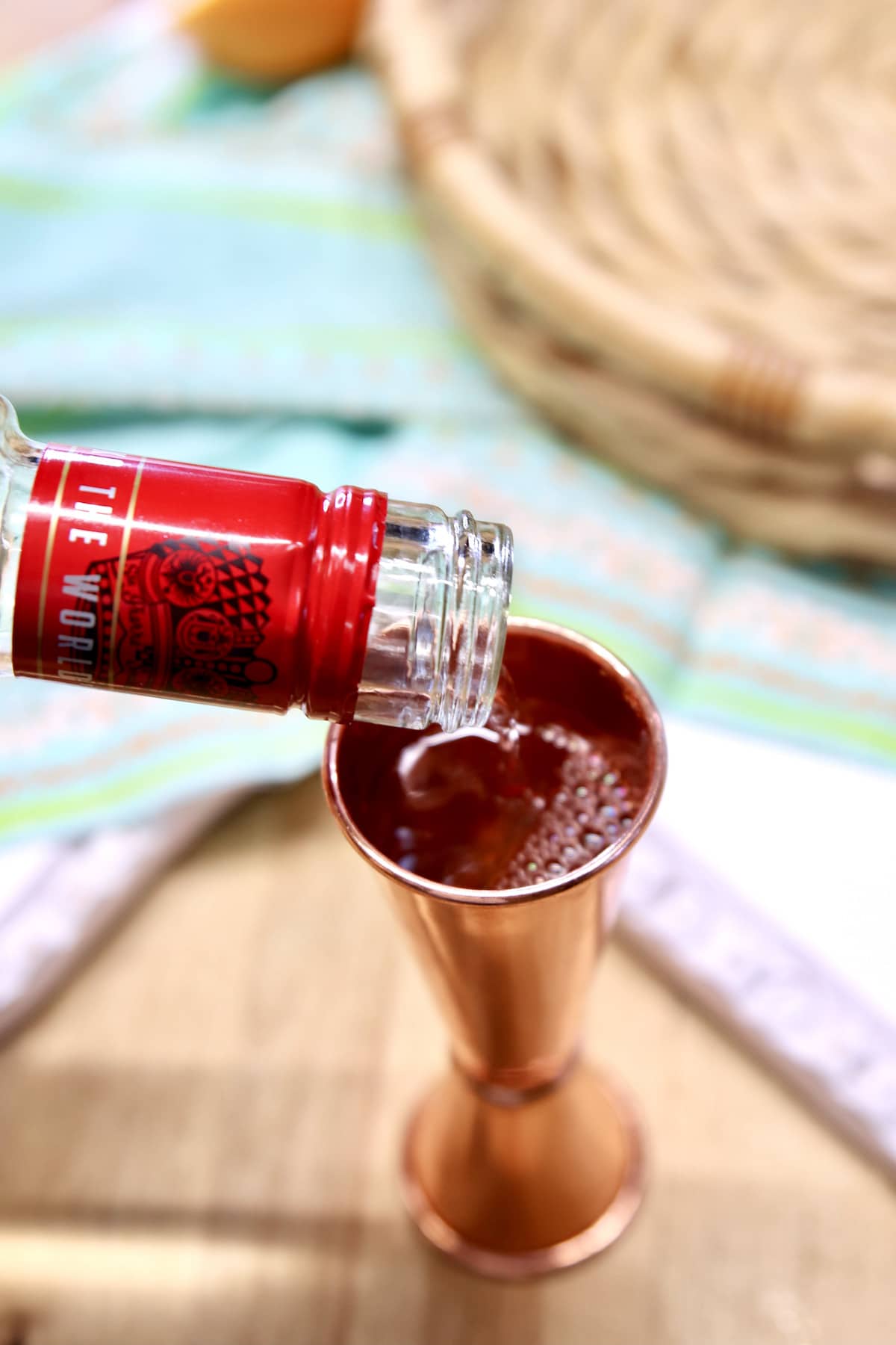 vodka pouring into a cocktail jigger.