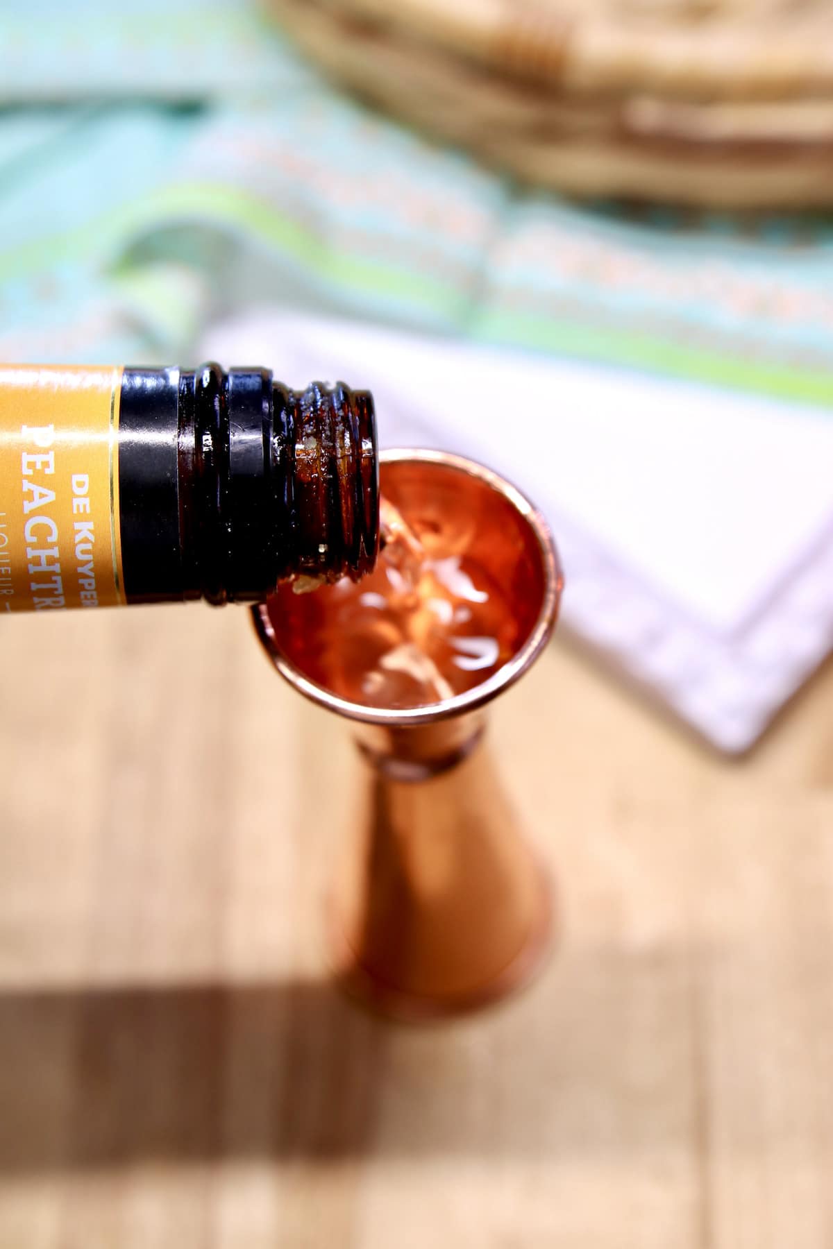 Measuring peach schnapps with a cocktail jigger.