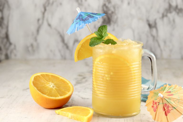 Brass Monkey Drink with orange, mint and umbrella garnish in a mug