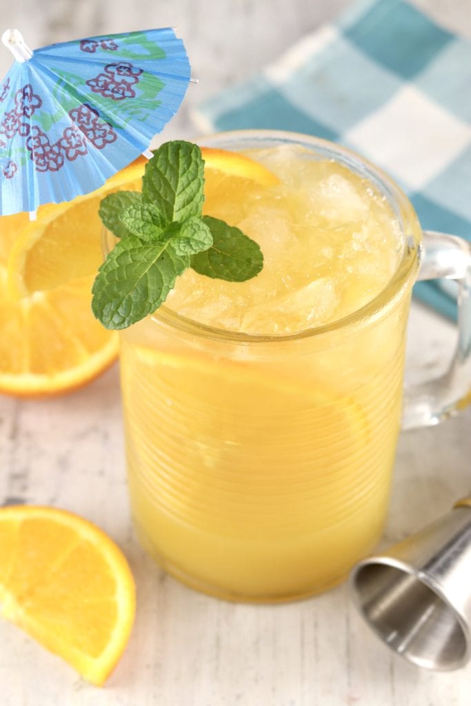 Brass Monkey Drink with orange and mint garnish + a blue drink umbrella