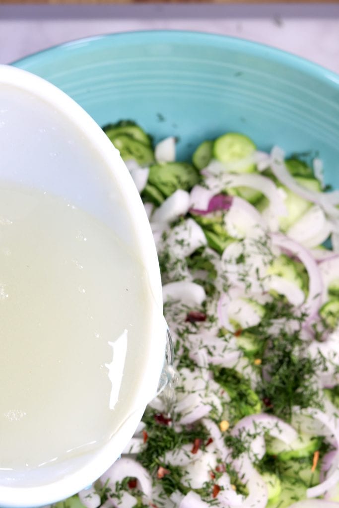 Pouring vinegar dressing over cucumber salad