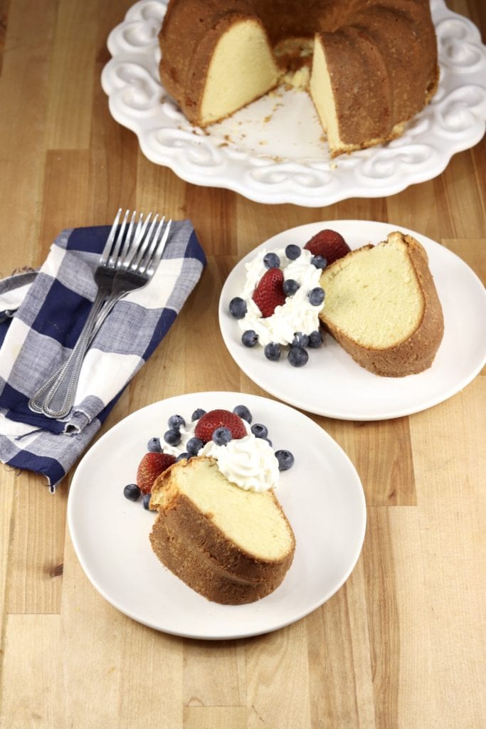 Million Dollar Pound Cake with fresh berries and whipped cream, 2 plates and cake plate with whole bundt cake
