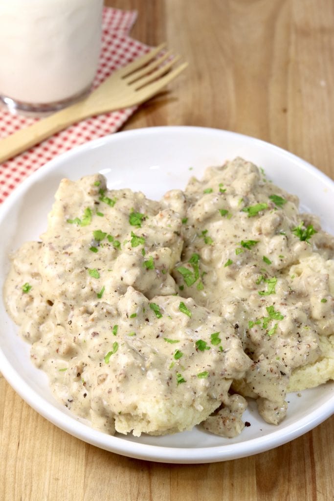 Plate of biscuits and sausage gravy with a glass of milk